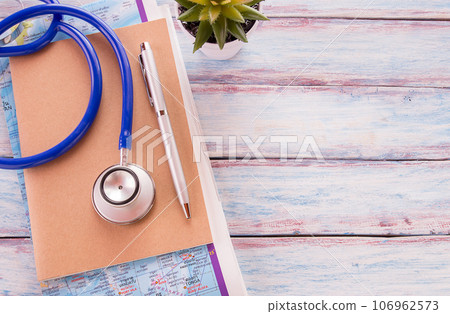 Flat lay photo with notebook, pen,map and blue stethoscope on wooden table background. 106962573