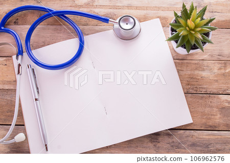Flat lay photo with blank notebook, pen and blue stethoscope on wooden table background. 106962576