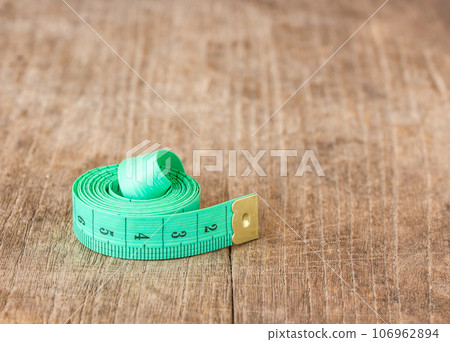 Close up green measuring tape on wooden table Close up green measuring tape on wooden table 106962894