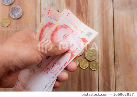 Singapore money in hand holding on wooden table background 106962937