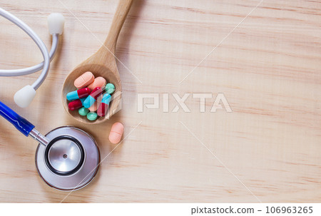 Close up blue stethoscope and pills in wood spoon 106963265