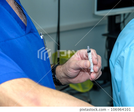 A small syringe in the hand of a doctor.  106964101