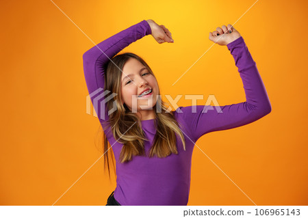 Photo of teen girl smiling portrait against yellow background in studio 106965143