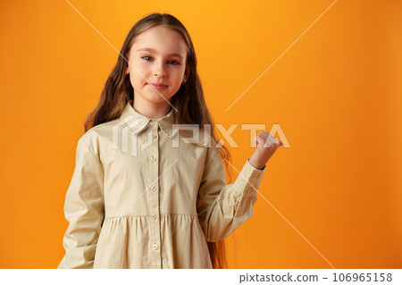 Teenager girl over yellow background pointing finger to copy space Teenager girl over yellow background pointing finger to copy space 106965158