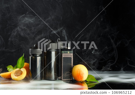 Vape and smoking liquid with fruit against black background with smoke Vape and smoking liquid with fruit against black background with smoke 106965212