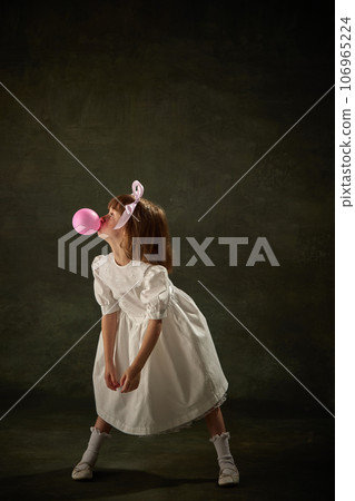Portrait of little girl blowing bubbles with gum, bubblegum chap over vintage background. Fairy princess character of storytale. Portrait of little girl blowing bubbles with gum, bubblegum chap over vintage background. Fairy princess character of storytale. 106965224