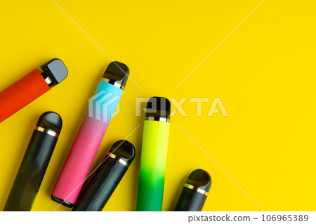 Colorful disposable electronic cigarettes on yellow background Colorful disposable electronic cigarettes on yellow background 106965389