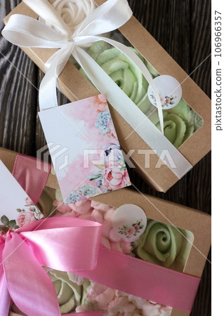 Two boxes with marshmallows. Zephyr flowers. Homemade marshmallows in a paper gift box. The box is tied with a ribbon tied into a bow. Label for the text. Close-up. Two boxes with marshmallows. Zephyr flowers. Homemade marshmallows in a paper gift box. The box is tied with a ribbon tied into a bow. Label for the text. Close-up. 106966357