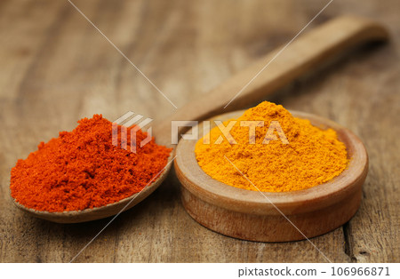 Ground turmeric and chili on wooden surface 106966871
