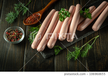 Boiled sausages on a serving board with dill and dry pepper for a delicious breakfast or dinner. Fast food sausages 106968655