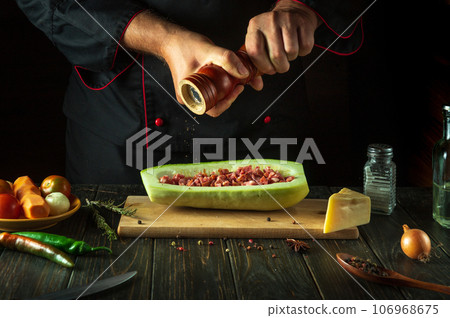 The chef adds pepper to the zucchini on the kitchen table. The concept of delicious national Stuffed squash or mahshi for lunch The chef adds pepper to the zucchini on the kitchen table. The concept of delicious national Stuffed squash or mahshi for lunch 106968675