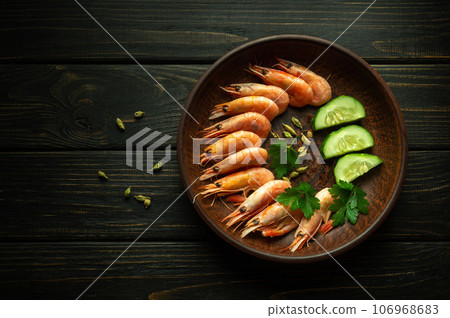 Boiled shrimp on a vintage plate with parsley and cucumbers. Hotel table setting concept or diet dinner with prawns. 106968683
