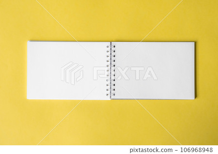 Opened notepad on a yellow background. Composition of writing to-dos for the day. The notebook lies on a plain background with space for writing. Opened notepad on a yellow background. Composition of writing to-dos for the day. The notebook lies on a plain background with space for writing. 106968948