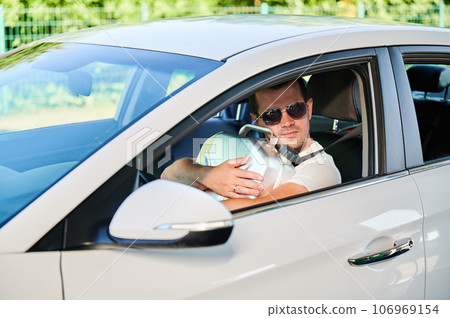 Happy man hugging canister full of gasoline. Man glad that took canister and have extra fuel for unforeseen circumstances. Smiling man in sunglasses sitting in white car and holding cistern. Happy man hugging canister full of gasoline. Man glad that took canister and have extra fuel for unforeseen circumstances. Smiling man in sunglasses sitting in white car and holding cistern. 106969154