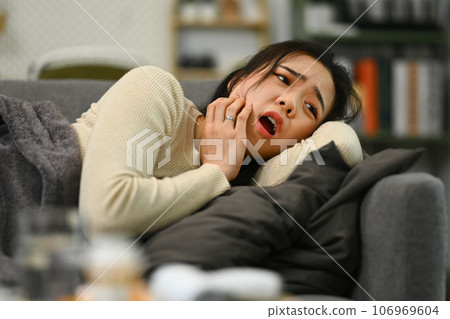 Unhappy young woman touching sore cheek suffering from toothache cavities or gingivitis symptoms. Dental health concept Unhappy young woman touching sore cheek suffering from toothache cavities or gingivitis symptoms. Dental health concept 106969604