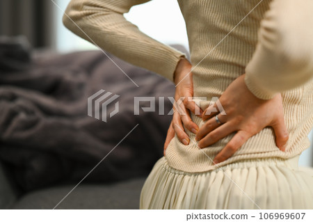 Unrecognizable woman suffering from lower lumbar backache, kidney disease, lumbar osteochondrosis, inflammation Unrecognizable woman suffering from lower lumbar backache, kidney disease, lumbar osteochondrosis, inflammation 106969607