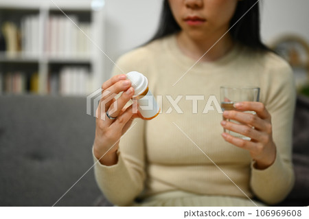 Sick young woman reading medicine instruction on packaging. Healthcare, medication concept Sick young woman reading medicine instruction on packaging. Healthcare, medication concept 106969608