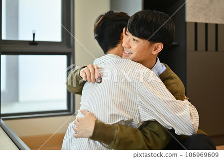 Loving gay man couple hugging each other in new house. LGBTQ, relocation and real estate property Loving gay man couple hugging each other in new house. LGBTQ, relocation and real estate property 106969609