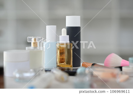 Closeup view of skincare product, lotion bottle, round mirror and makeup brushes on dressing table Closeup view of skincare product, lotion bottle, round mirror and makeup brushes on dressing table 106969611