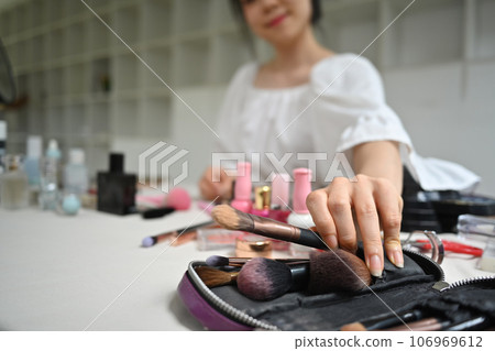 Beauty blogger hand holding a makeup brush while doing makeup at home. Beauty cosmetics and blogger Beauty blogger hand holding a makeup brush while doing makeup at home. Beauty cosmetics and blogger 106969612