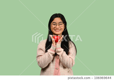 Smiling asian girl hands holding red heart over green background. Health care, insurance, love, charity and donation concept 106969644
