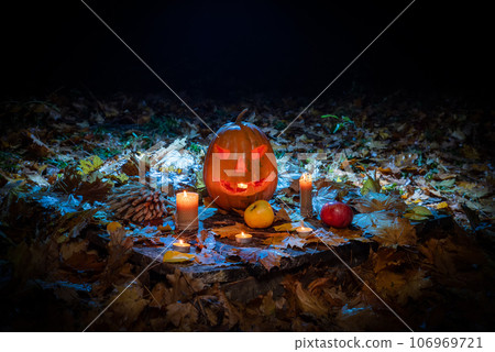 Halloween pumpkin with candle closeup in dark forest. Halloween festive background 106969721