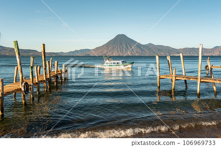 Wooden docks on Lake Atitlan on the beach in Panajachel, Guatemala. With Toliman and San Pedro volcanoes in the background 106969733
