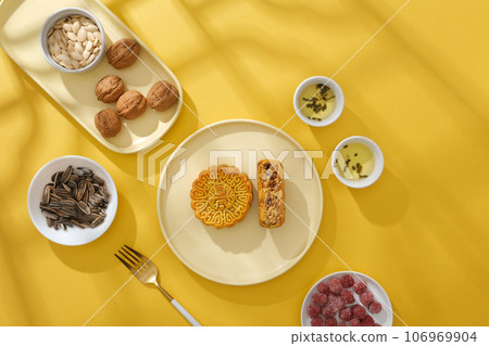 Scene for advertising mooncake on yellow background. Traditional foods on the Mid-Autumn Festival decorated. Mid-Autumn Festival is also an opportunity for generations of families to reunite Scene for advertising mooncake on yellow background. Traditional foods on the Mid-Autumn Festival decorated. Mid-Autumn Festival is also an opportunity for generations of families to reunite 106969904