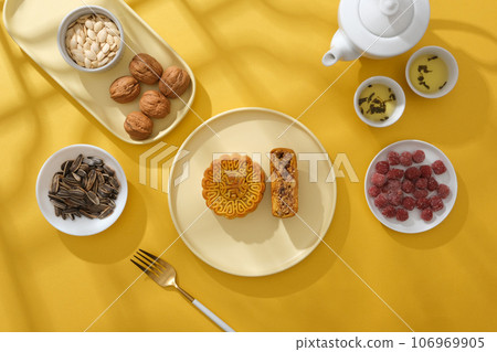 Against the yellow background, delicious mooncakes and traditional foods on Mid-autumn festival decorated. Mid-Autumn Festival is an important and colorful traditional festival. Advertising photo Against the yellow background, delicious mooncakes and traditional foods on Mid-autumn festival decorated. Mid-Autumn Festival is an important and colorful traditional festival. Advertising photo 106969905