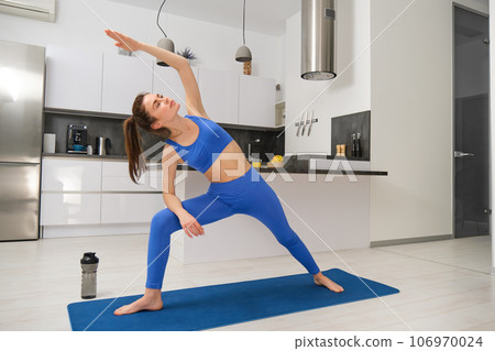 Portrait of young fitness instructor, woman doing yoga, standing in asana on rubber mat, workout at home Portrait of young fitness instructor, woman doing yoga, standing in asana on rubber mat, workout at home 106970024