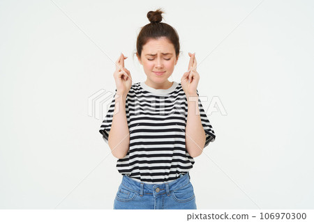Portrait of hopeful young woman, makes wish, cross fingers for good luck, wishing, anticipating, standing over white background Portrait of hopeful young woman, makes wish, cross fingers for good luck, wishing, anticipating, standing over white background 106970300