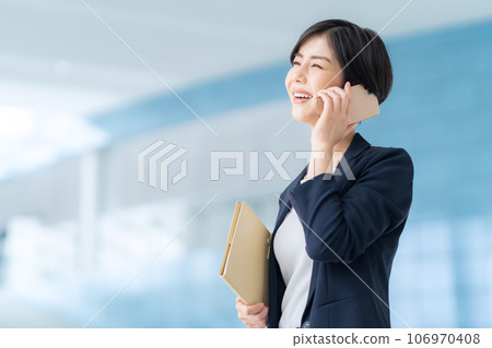 年輕女商人在辦公室打電話用智能手機 年輕女商人在辦公室打電話用智能手機 106970408