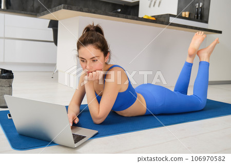 Image of young sportswoman, fitness girl watching online yoga tutorial on laptop and exercising, following video instructions Image of young sportswoman, fitness girl watching online yoga tutorial on laptop and exercising, following video instructions 106970582