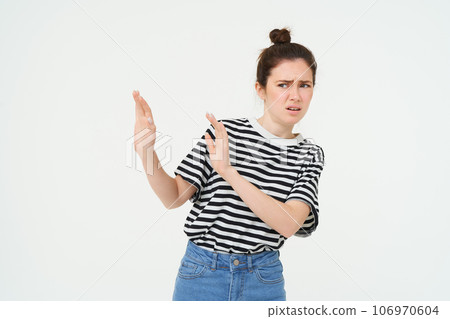 Image of woman expressing aversion, dislike something, looks apalled, extends hands forward in defensive gesture, rejecting, refusing, standing over white background 106970604