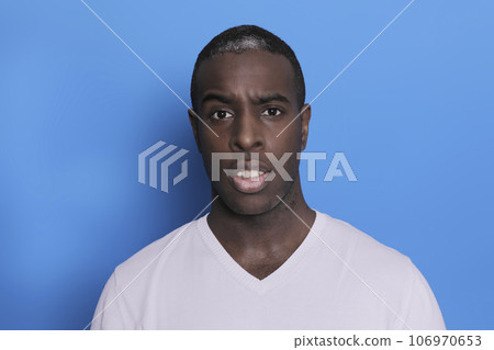 Portrait of cheerful young african-american guy wearing white casual sweater posing isolated on blue background Portrait of cheerful young african-american guy wearing white casual sweater posing isolated on blue background 106970653