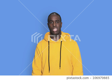 Young sad frustrated worried man in yellow hoodie looking camera isolated on blue wall background studio portrait Young sad frustrated worried man in yellow hoodie looking camera isolated on blue wall background studio portrait 106970665