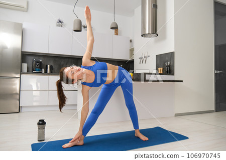 Portrait of young fitness instructor, woman doing yoga, standing in asana on rubber mat, workout at home Portrait of young fitness instructor, woman doing yoga, standing in asana on rubber mat, workout at home 106970745