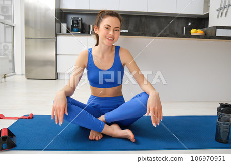 Yoga, welness and wellbeing. Young woman workout, does sport at home, female fitness instructor stretches before exercises on rubber mat in living room 106970951