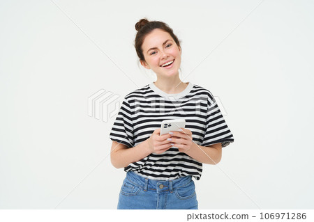 Image of young smiling woman, holding mobile phone, using smartphone application, isolated over white background Image of young smiling woman, holding mobile phone, using smartphone application, isolated over white background 106971286