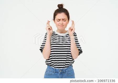 Nervous girl, student cross fingers for good luck, making wish, hoping for something, anticipating positive results, standing over white background Nervous girl, student cross fingers for good luck, making wish, hoping for something, anticipating positive results, standing over white background 106971336