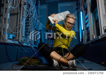 Frustrated angry female IT technician throwing computer keyboard in server room Frustrated angry female IT technician throwing computer keyboard in server room 106971798