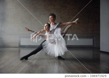 Woman and man ballet dancers in dynamic action against studio background 106971929