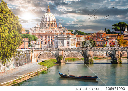 Sunset view of Tiber River in Rome, Italy, featuring St. Peter's Basilica, boats, and Renaissance architecture. 106971990