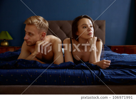 Sad unhappy couple lying in home bed having relationship difficulties Sad unhappy couple lying in home bed having relationship difficulties 106971991