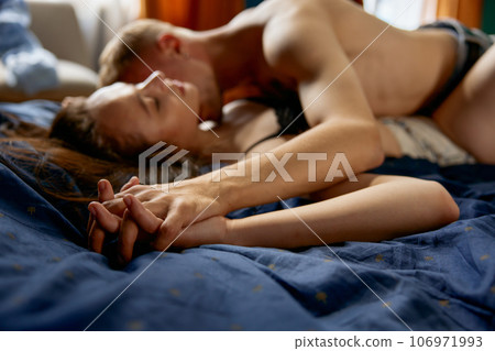 Young millennial couple lying in bed at home, man kissing woman with passion Young millennial couple lying in bed at home, man kissing woman with passion 106971993