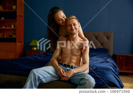 Happy smiling loving couple sitting and cuddling in bed 106971998
