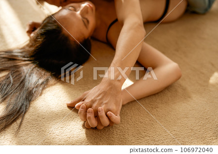 Sexy romantic couple lying on floor embracing and kissing focus on hands Sexy romantic couple lying on floor embracing and kissing focus on hands 106972040