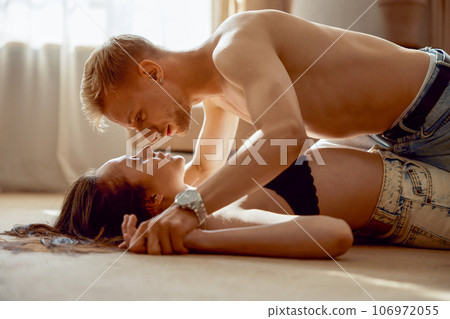 Young half naked man woman passionate lovers lying on floor and kissing 106972055