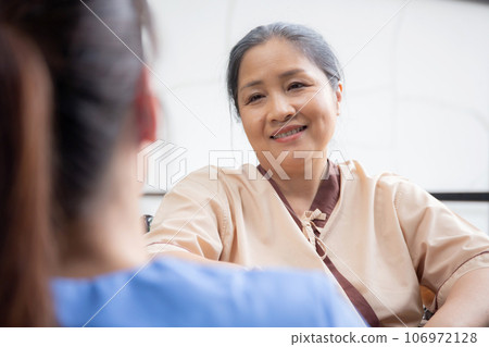Caregiver asian woman care elderly sitting on wheelchair, consoling for encourage in garden. 106972128