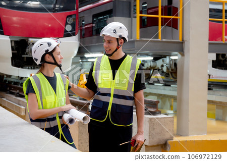 Young caucasian engineer man and woman meeting and checking electric train for planning maintenance. 106972129